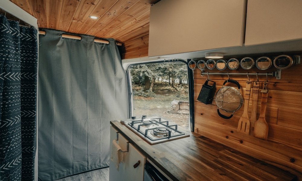 Inside of a van showing wood panelling and a stove 