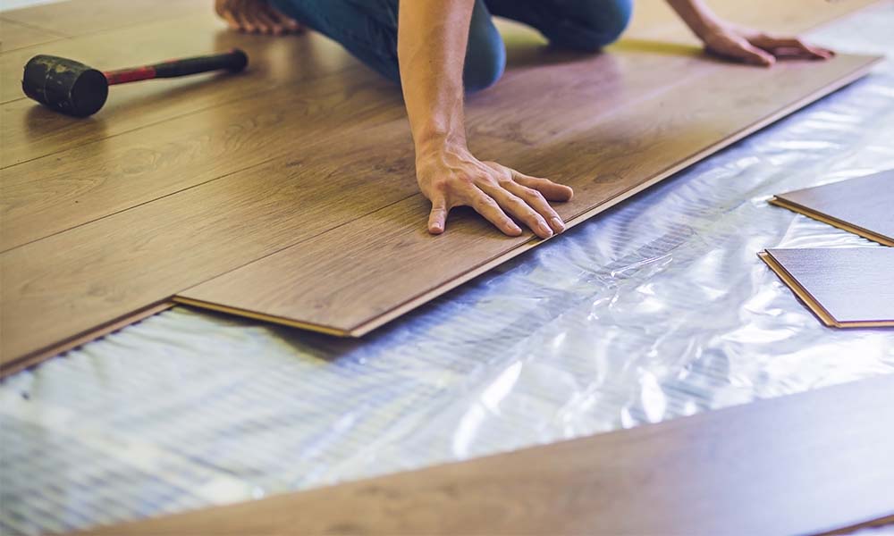 man installing laminate planks over underfloor heating