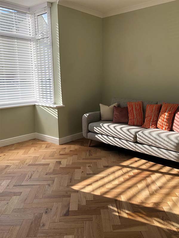green walls, herringbone floor and grey sofa 