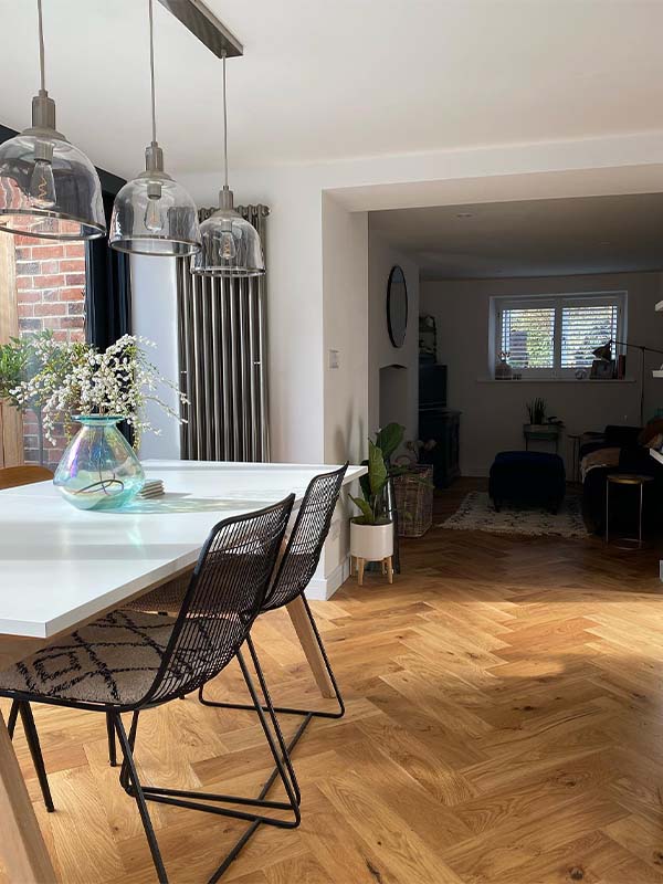 herringbone flooring with white table and wired chairs 