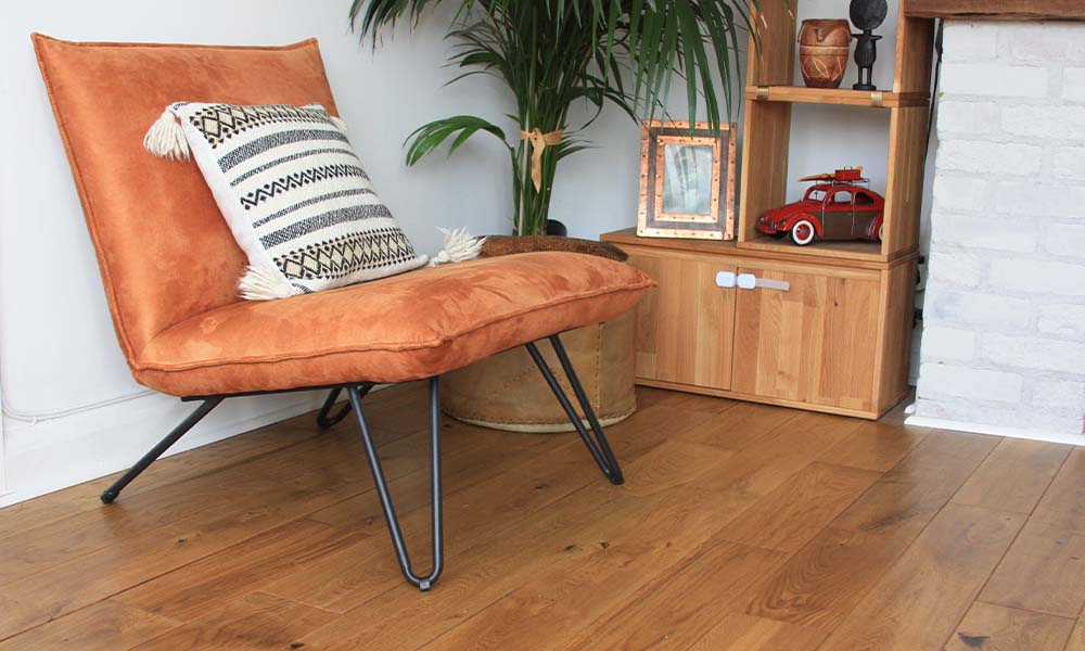 orange suede chair, plants, wooden bookshelf and hand-scraped wood floor 