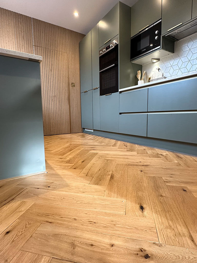 Dark coloured kitchen with golden herringbone floor