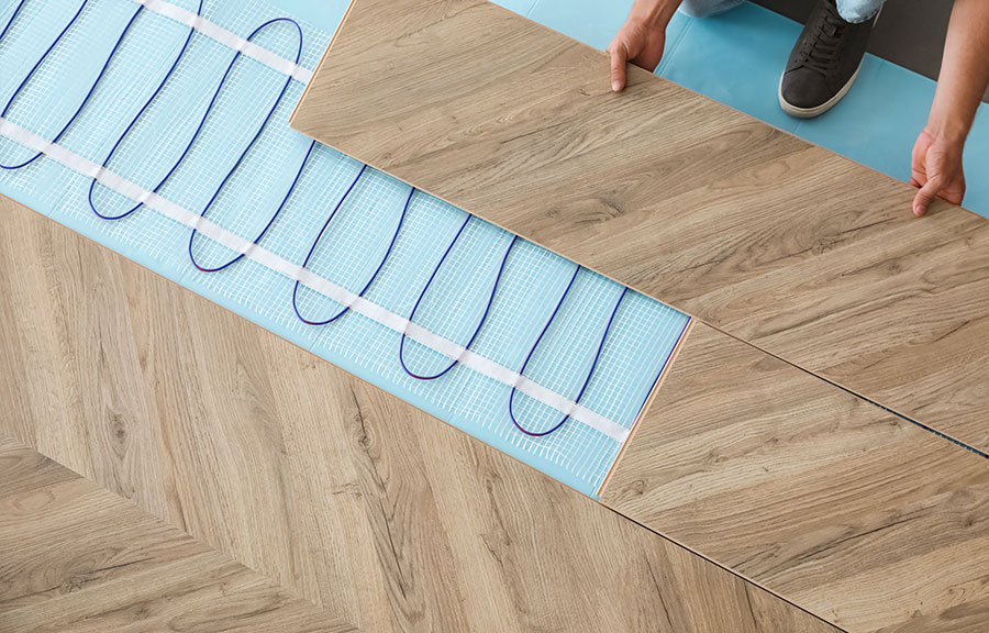man putting floor boards on top of underfloor heating cables
