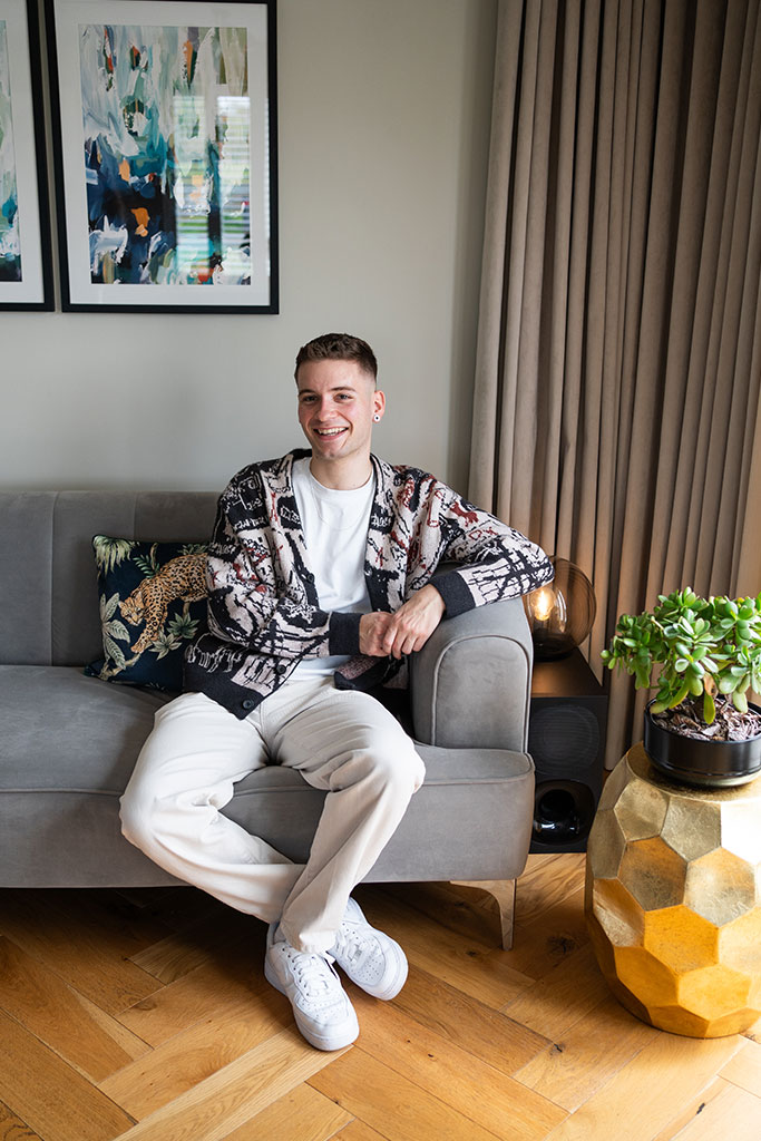 Happy man sat smiling on grey sofa in living room