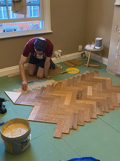 Man gluing down herringbone in living room