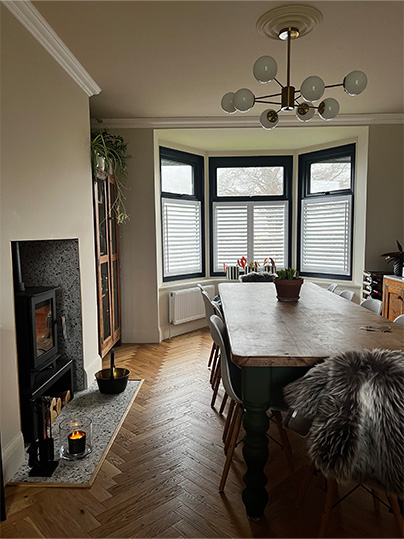 Open plan dining room with large bay window and cosy fireplace