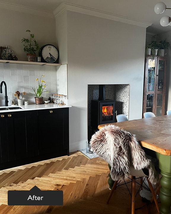Cosy open plan dining room with warm toned herringbone, wooden table and roaring fire